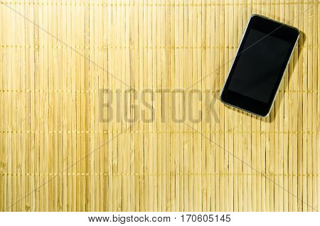 Black Smart Phone on The Bamboo Background. Use for Texture and Wallpaper.