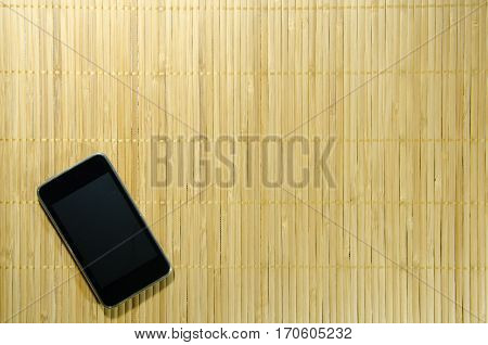 Black Smart Phone on The Bamboo Background. Use for Texture and Wallpaper.