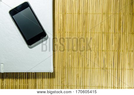 Black Smart Phone on The Bamboo Background. Use for Texture and Wallpaper.