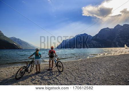 Mountain biking woman and young girl over Lake Garda.