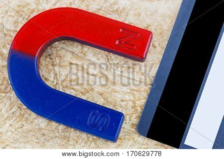 Closeup of magnet pulling credit card on fiber paper background