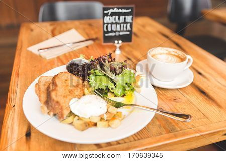 Eggs potatoes lettuce toast and coffee in a breakfast meal spread. Upscale cafe setting.