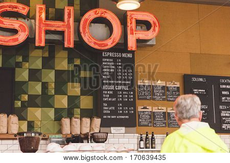 Cafe menu on wall with customer at counter in modern upscale cafe.