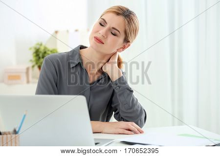 Beautiful woman suffering from neck pain in office