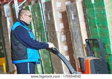 Worker with pallet truck stacking cardboxes