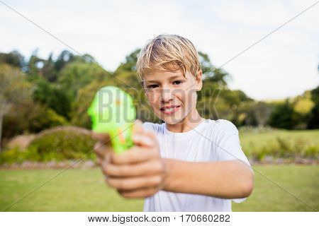 Kid posing at camera during a sunny day with his water gun at park