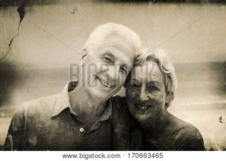 Grey background against portrait of senior couple embracing at beach