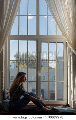 redhead girl thinks on the big window