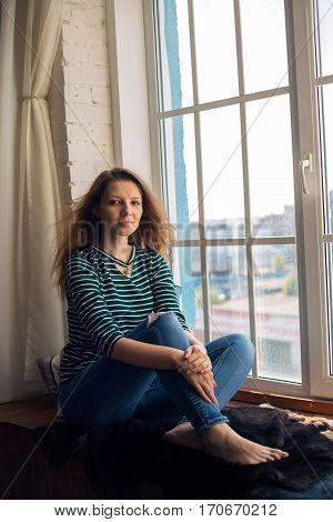 big window and redhead young woman sitting