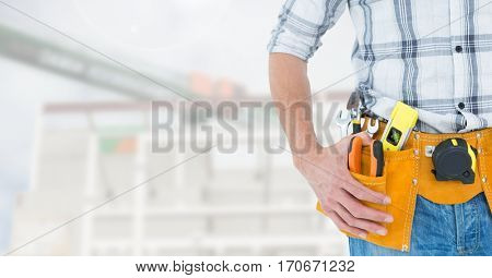 Mid section of handyman with hands on hip and tool belt