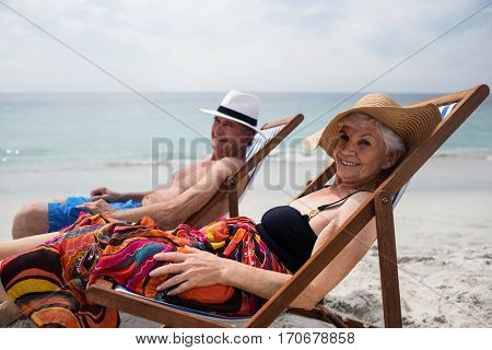 Happy senior couple relaxing on deckchairs at beach on a sunny day