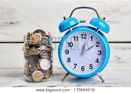 Alarm clock and coins. Time to make credit payment.