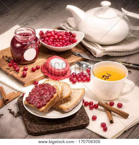 Lingonberry jam bread and tea composition on a wooden background