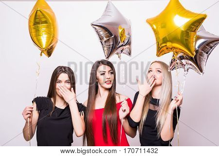 Three Lovely Young Women Have Fun And Holding Star Shaped Balloons Over White