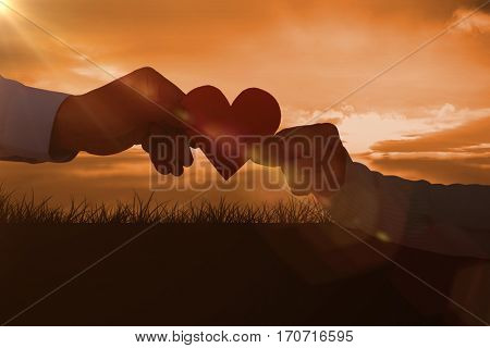 Couple holding paper heart shape paper against a couldy day