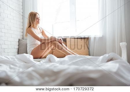 Young Smiling Woman sitting near the window in bedroom