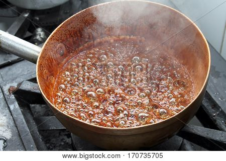Copper pan turning sugar into caramel hot
