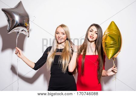 Two happy attractive yougn women having party over white background