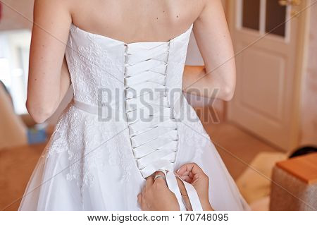 bridesmaid helping to dress the bride in a wedding morning.