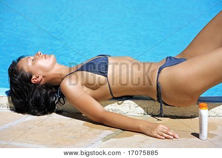 Young beautiful caucasian brunette Woman entspannen oder schlafen, nahe einem Schwimmbecken, die immer von gegerbt