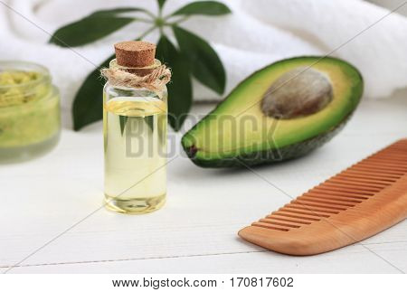 Avocado oil in bottle, green fruit, comb. Cosmetic benefits, healthy hair and skin care.