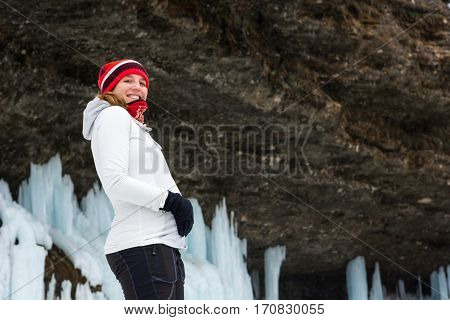 Young pregnant woman smiling on winter landscape. Icicles and snow in the background.