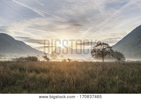 Beautiful Foggy Misty Autumn Sunrise Over Countryside Surrounding Crummock Water In Lake District In