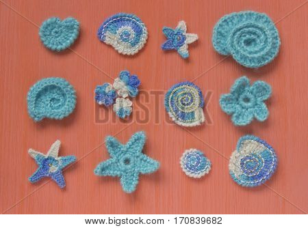 Marine background with cotton lace crochet craft elements: stars shells flowers made of soft acrylic wool yarn. Crocheted creative doilies. Decorative needlework marine design. Selective soft focus