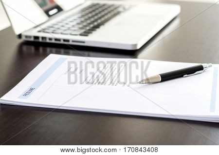 Close-up Of Resume, Pen And Computer Laptop On Black Wooden Desk.