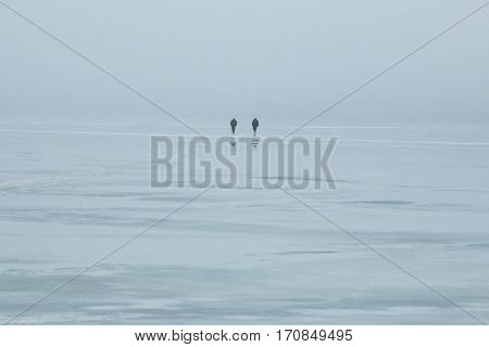 Belarus-March 7 2016 Fishermen are on the river ice to the shore after a failed catch spring fog the last ice sunset in the fog