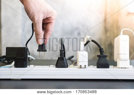 Hand holding electric plug Multiple socket with connected plugs.