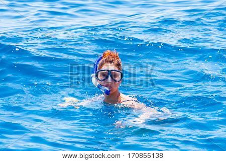 happy woman wearing a mask in the sea along with a camera.