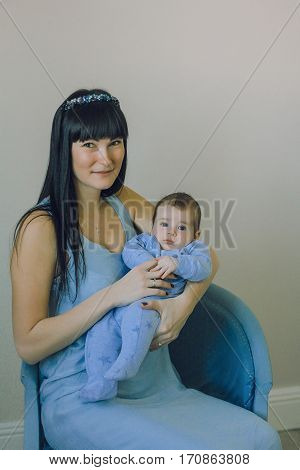 happy mother in a blue dress with a hoop and a baby