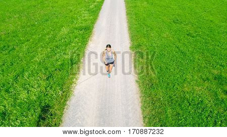 aerial view of young woman jogging in the fields
