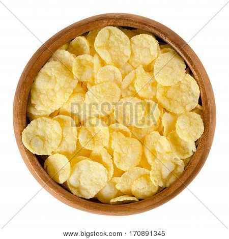 Corn flakes in wooden bowl. Crispy cornflakes, a popular breakfast cereal made by toasting small flakes of corn. Isolated macro food photo close up from above on white background.