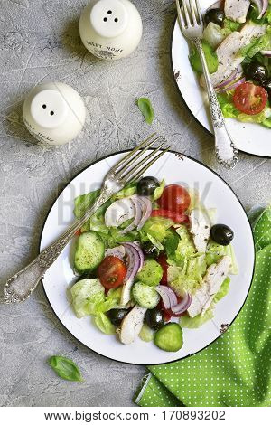 Vegetable Salad With Chicken And Black Olives On A White Plate.