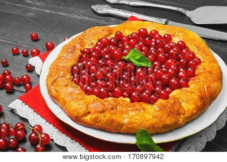 Open pies tart with berries red currant. Fresh red currant berries for Open pies tart mint red lace cloth. Dark black wooden background