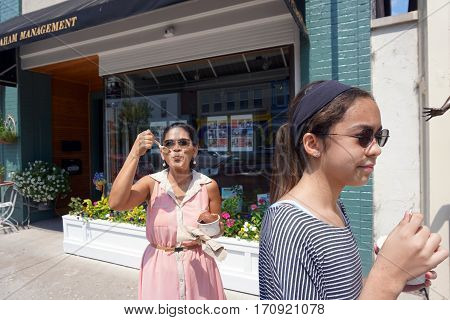 HARBOR SPRINGS, MICHIGAN / UNITED STATES - AUGUST 4, 2016: A woman eats a big bowl of Kilwin's chocolate ice cream while walking on Main Street in downtown Harbor Springs.