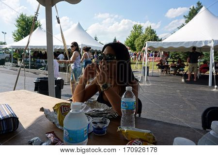 JOLIET, ILLINOIS / UNITED STATES - JUNE 25, 2016: A woman eats a sandwich at the Wesmere Country Club Subdivision's annual Wesmere Summerfest in Joliet.
