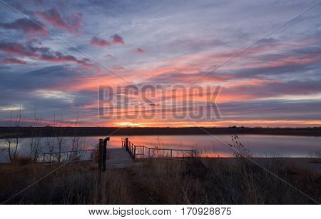 The sky bursts with color at sunrise on Lon Hagler Reservoir in Loveland Colorado