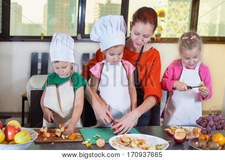 Three Cute Kids Are Preparing A Fruit Salad In Kitchen