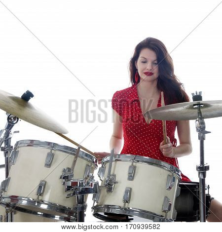 sexy brunette in red dress plays drum kit in studio against white background