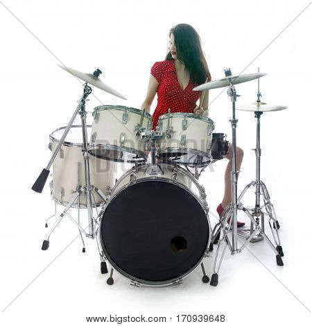 sexy brunette in red dress plays drum kit in studio against white background