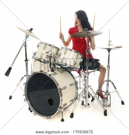 sexy brunette in red dress plays drum kit in studio against white background