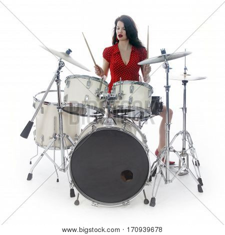 sexy brunette in red dress plays drum kit in studio against white background