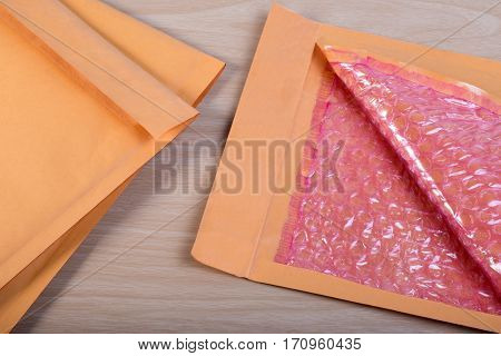 Open Used Yellow Blank Envelope With Transparent Bubble Wrap Or Packaging Shockproof On Wooden Table