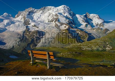 Scenic bench view over the snowy mountains Pennine Alps Switzerland