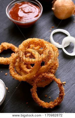 Crispy fried onion rings on dark background