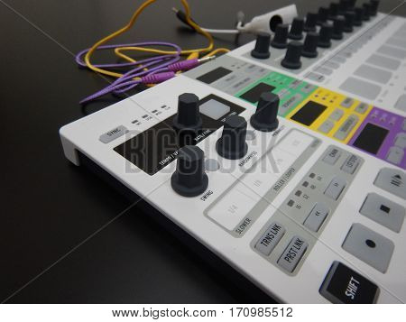 white Synthesizer with knobs and patch cables around it