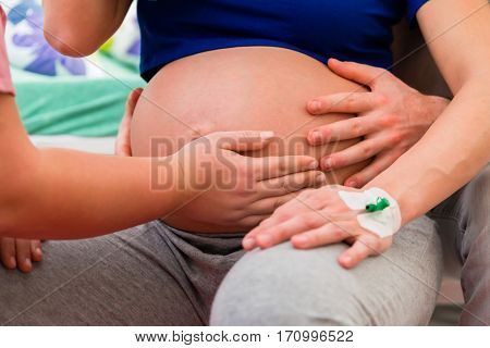 Midwife or nurse feeling baby belly of pregnant woman